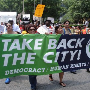 Protesters demonstrate while holding a banner saying "Take Back the City!"