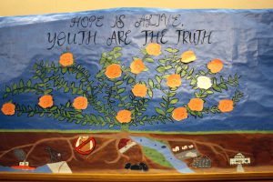 Banner of flowering plant with images of pollution, urbanization, and the White House at the roots. The words "Hope is alive. Youth are the truth." at the top.