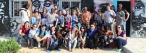 Group of students pose in front of mural of portraits on building in Senegal