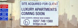 Sign on concrete wall saying site will soon be luxury apartments