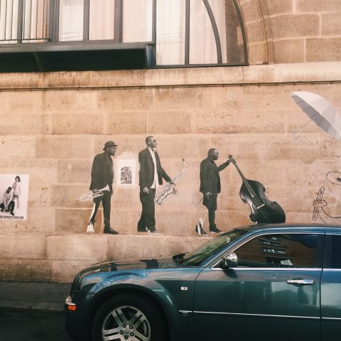 Mural of three jazz musicians on a tan brick wall